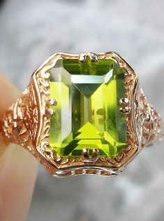 Make heads turn and stand out with this gorgeous piece of jewelry! This Edwardian reproduction filigree ring is made from rose gold and features an emerald cut high quality natural green Peridot gemstone measuring 9mm by 7mm. From the beautiful intricate floral daisy design to the inside of the band marked 10K or 14K for gold – this ring will take your look to the next level Victorian Green Jewelry Stamped 14k, Art Deco Green Octagon Jewelry, Green 14k Gold Rings With Intricate Design, Victorian Style Gold Jewelry With Emerald Cut, 14k Gold Green Rings With Intricate Design, Victorian 14k Stamped Green Jewelry, Victorian Yellow Gold Jewelry With Accent Stones, Gold Peridot Jewelry With Emerald Cut, Vintage Gold Peridot Jewelry