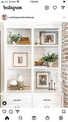 a white bookcase filled with pictures and other items on top of a brick wall