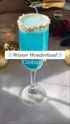 a glass filled with blue liquid sitting on top of a table next to christmas decorations