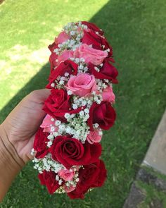 a hand holding a bouquet of red and pink roses