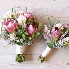 two bouquets of flowers sitting on top of a wooden floor next to each other