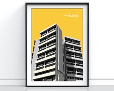 an art print of a high rise building in yellow and grey, against a white wall