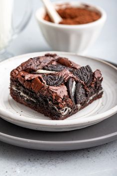 a white plate topped with two brownies and a cup of chocolate cake next to it