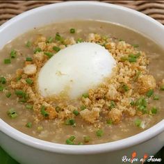 a white bowl filled with soup topped with an egg and green onions on the side