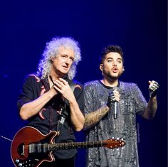 two men standing next to each other on stage with microphones in front of them