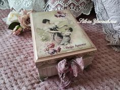 an antique box is sitting on the floor next to some laces and pink flowers