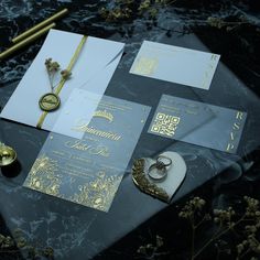 the wedding stationery is laid out on top of the table with gold and silver accents