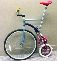 a blue and pink bike leaning against a wall