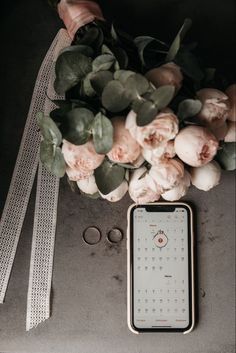 a bouquet of flowers sitting next to a cell phone on top of a gray surface