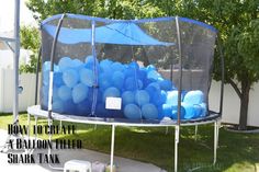 a blue trampoline filled with balloons in the yard