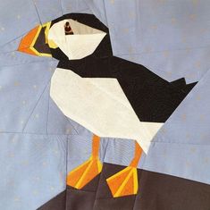 a close up of a quilt with a bird on it's back and yellow feet