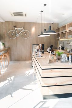 a bike hanging from the ceiling in a kitchen with wooden cabinets and counter tops, along with stools