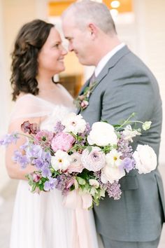 a bride and groom are standing together in front of a building with flowers on it