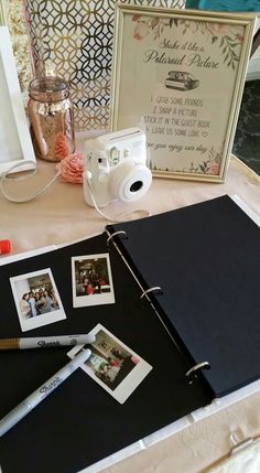 an open photo album sitting on top of a table next to a camera and other items