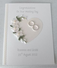 a wedding card with white flowers and two circles on it, in the shape of a heart