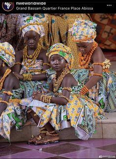 four women dressed in african clothing sitting on steps