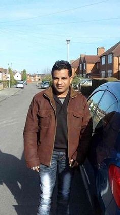 a man standing next to his car on the street