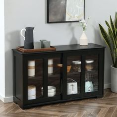 a black cabinet with glass doors on the top and bottom, next to a potted plant