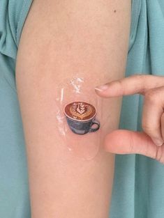 a woman's arm with a cup of coffee tattoo on it