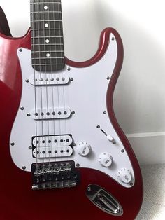 a red electric guitar sitting on the floor