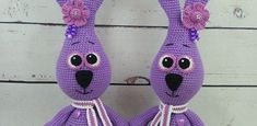 two purple stuffed animals sitting next to each other on top of a white wooden floor