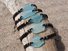 four pieces of sea glass sitting on top of a piece of driftwood with black cords