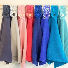 there are many different colors of towels hanging on the clothes rack with wooden pegs