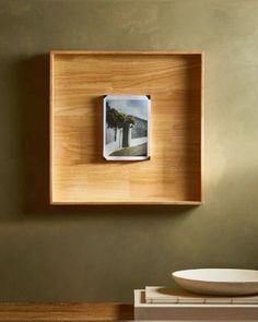 a wooden frame with a photo hanging on the wall next to a bowl and plate