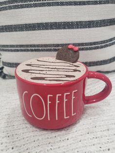 a red coffee cup with a chocolate cookie on top and the word coffee written in white