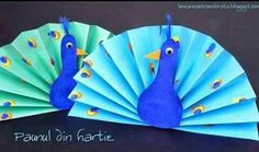 two paper fans with peacocks on them sitting next to each other in front of a black background