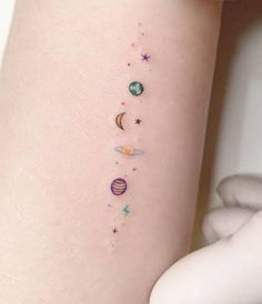 a woman's arm with tattoos that have planets and stars painted on the side