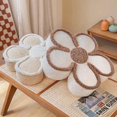 three flower shaped pillows sitting on top of a wooden table next to a magazine rack