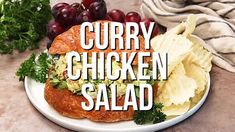 the words curry chicken salad are displayed on a plate with grapes and croissants