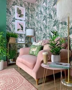 a living room with pink couches, green walls and palm leaves on the wall