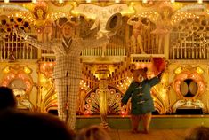 a woman standing in front of a stage with lights on it's sides and an elephant statue behind her