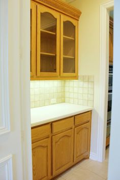 an empty kitchen with wooden cabinets and white counter tops in the middle of the room