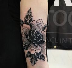 a black and white flower tattoo on the arm