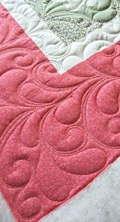 a close up of a pink and white quilt