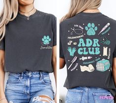 a woman wearing an adr club t - shirt and ripped jeans with her hands on her hips