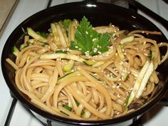 a pan filled with noodles and vegetables on top of a stove