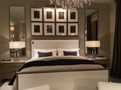 a large bed sitting under a chandelier next to a bedroom with pictures on the wall