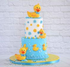 a three tiered cake with rubber ducks on the top and blue, yellow and white icing