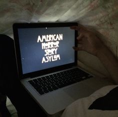 an open laptop computer sitting on top of a bed next to someone's feet