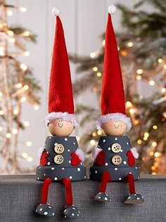 two red and white elfs are standing next to each other with christmas lights in the background