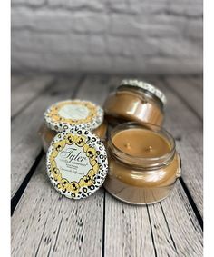 three jars of candles sitting on top of a wooden table