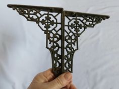 a hand holding an ornate iron shelf bracket