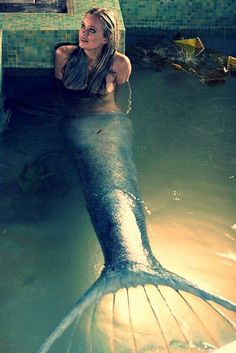 a woman is sitting in the water with a mermaid tail