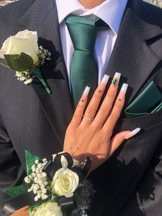 a man in a suit and tie with his hands on his lapel holding a white rose