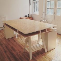 an empty room with wooden floors and a large table in the center, next to a radiator