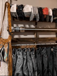 several pairs of jeans are hanging on a rack next to a purse and other items